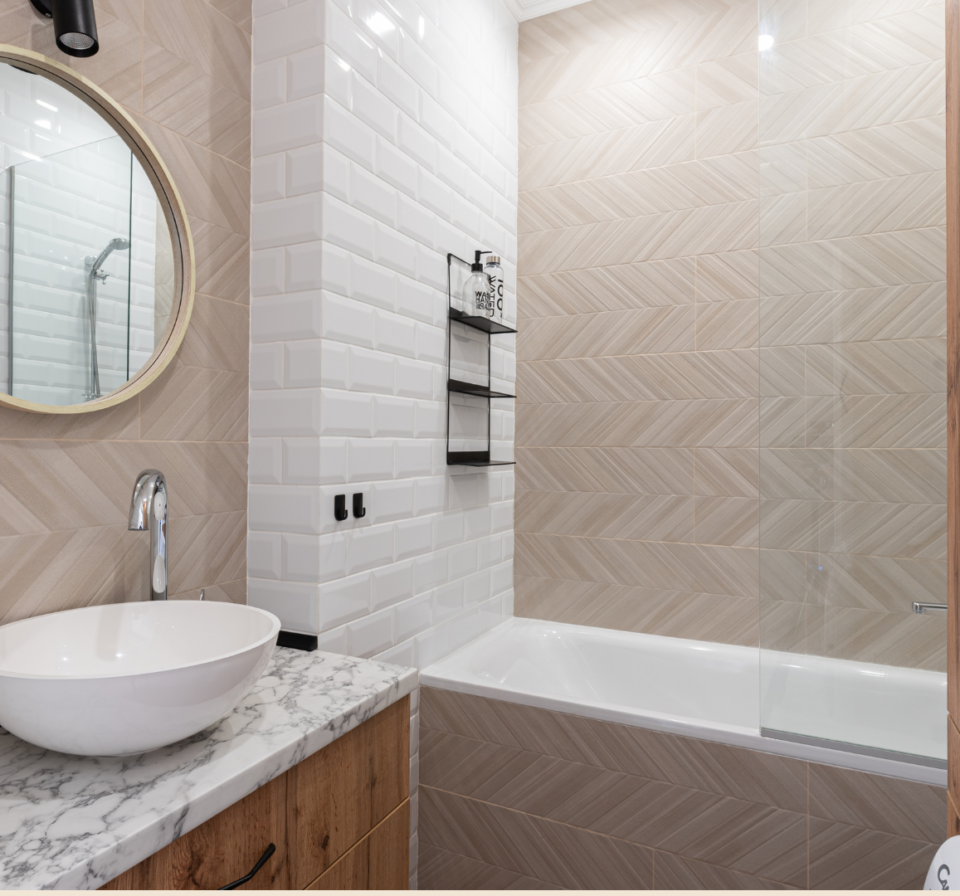 Newly installed bathroom tiles with a craftsman using a tool to cut tiles for a perfect fit during installation.